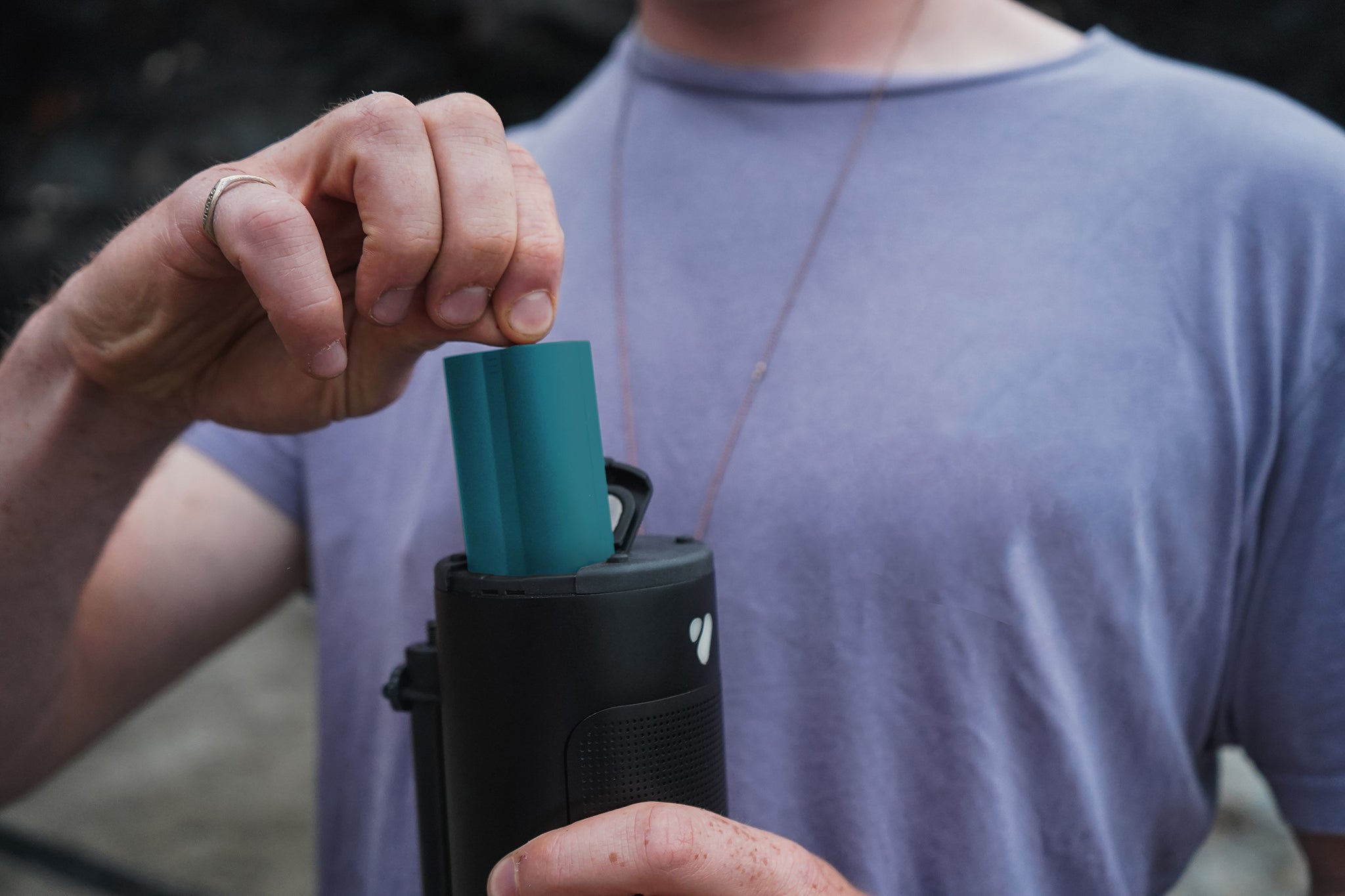 Person pulling a blue swappable battery from a black portable speaker.