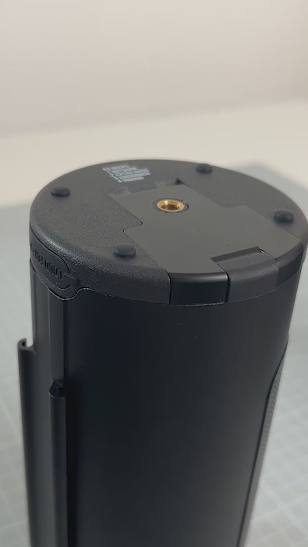 Load video: A close-up instructional video showing hands demonstrating how to lock and unlock the battery compartment of the PINE Beat Bluetooth speaker. The video begins with the speaker resting on a table, then two hands come into shot, one hand holds the speaker in place and the other hand pulls the lock out and gently pushes it up. The hands then hold the speaker firmly and both the right and left thumb rest on either side of the lock and push up firmly to release the lid and seal.