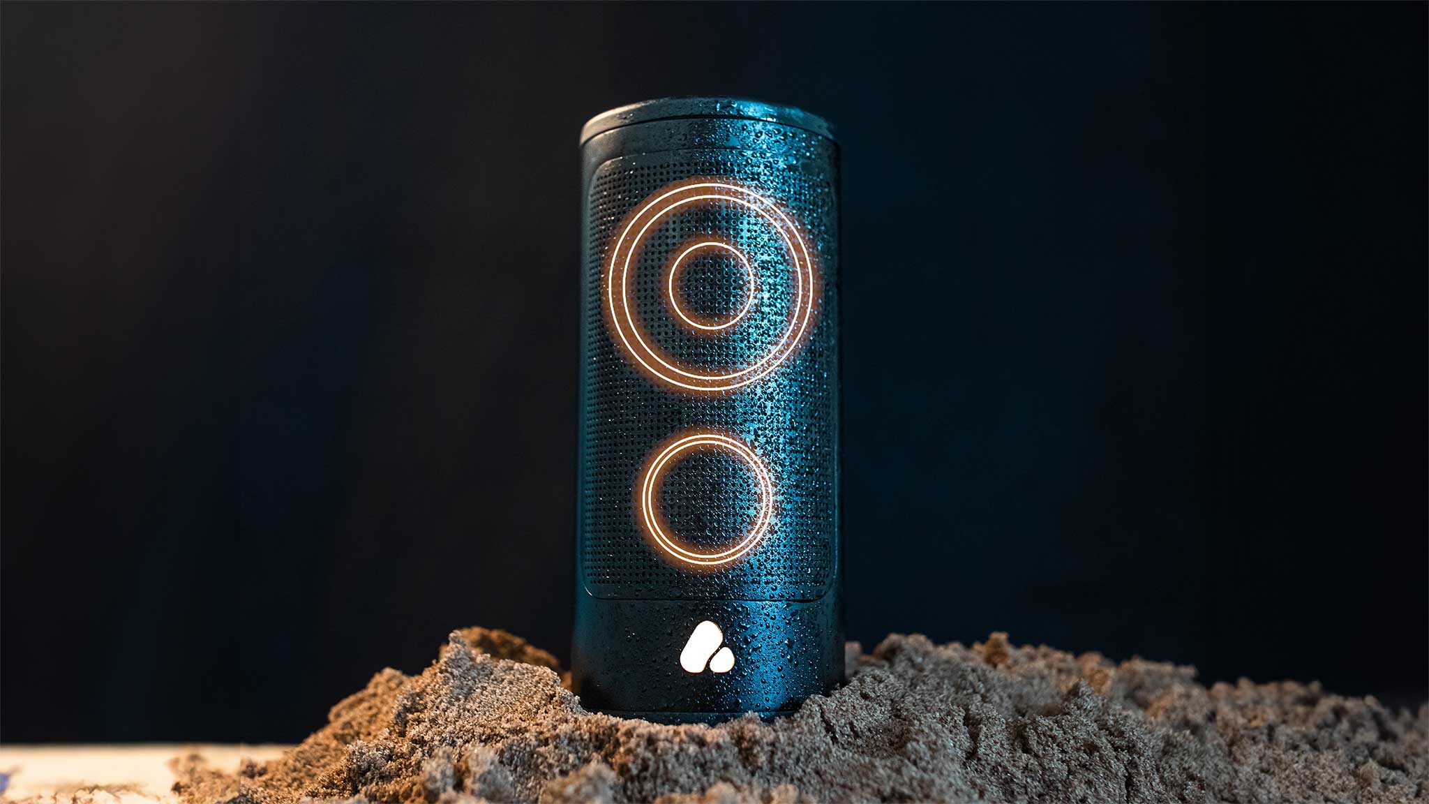 Cylindrical black speaker with glowing circles on a dark background
