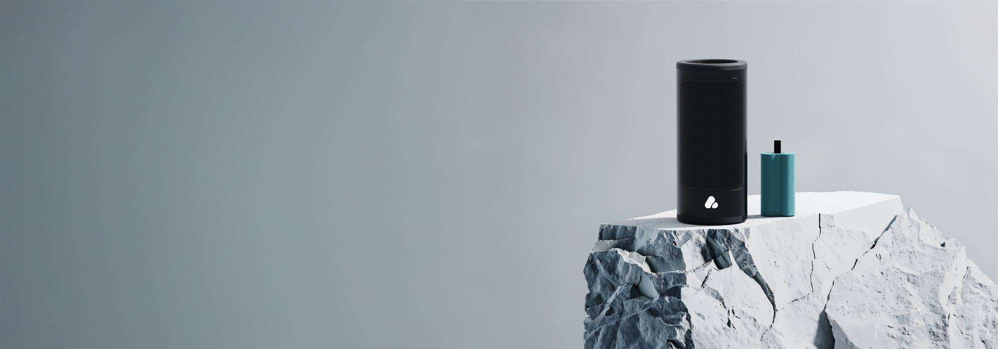 Black portable speaker and blue battery on rocky surface and grey background 