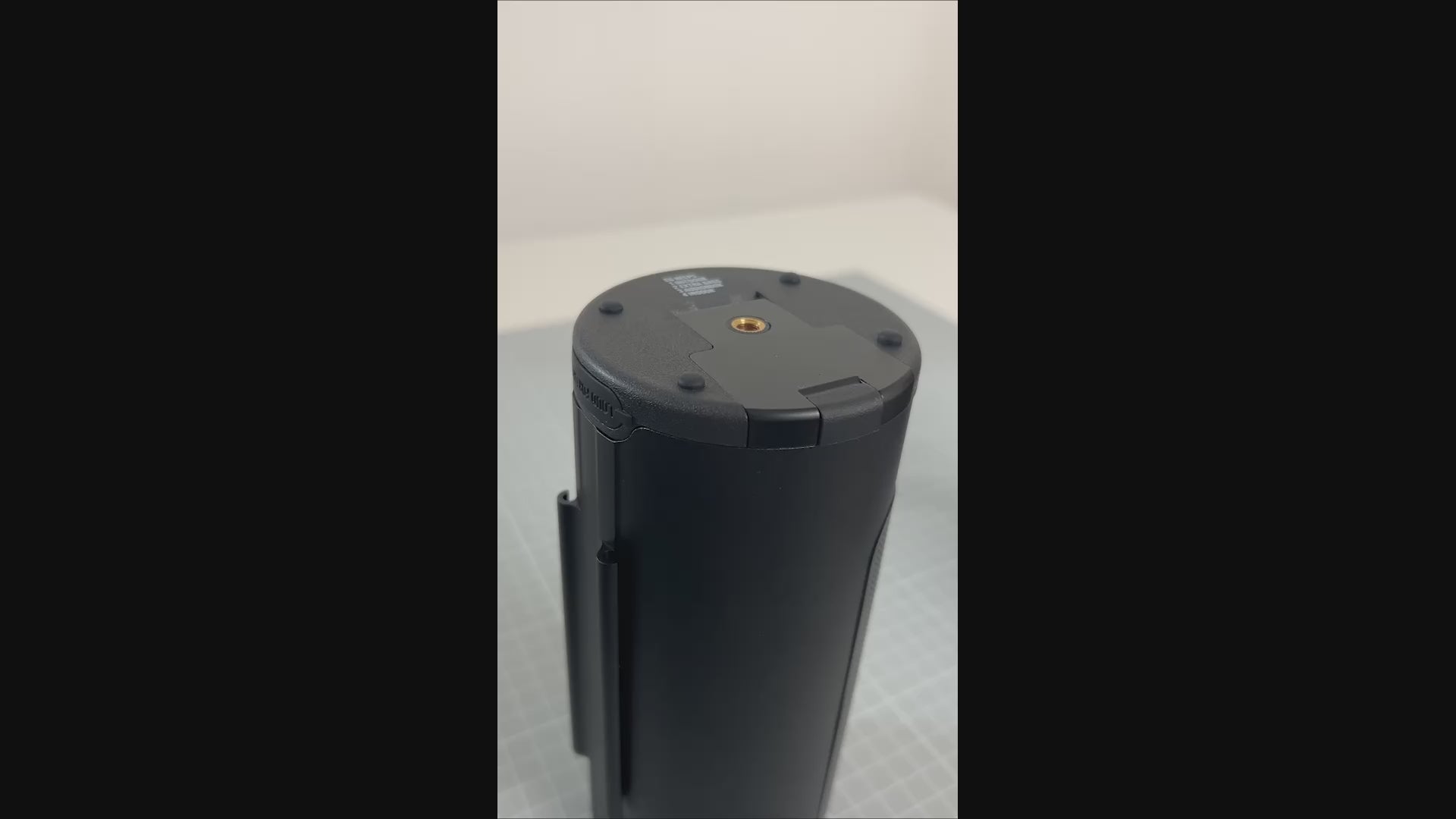 Load video: A close-up instructional video showing hands demonstrating how to lock and unlock the battery compartment of the PINE Beat Bluetooth speaker. The video begins with the speaker resting on a table, then two hands come into shot, one hand holds the speaker in place and the other hand pulls the lock out and gently pushes it up. The hands then hold the speaker firmly and both the right and left thumb rest on either side of the lock and push up firmly to release the lid and seal.
